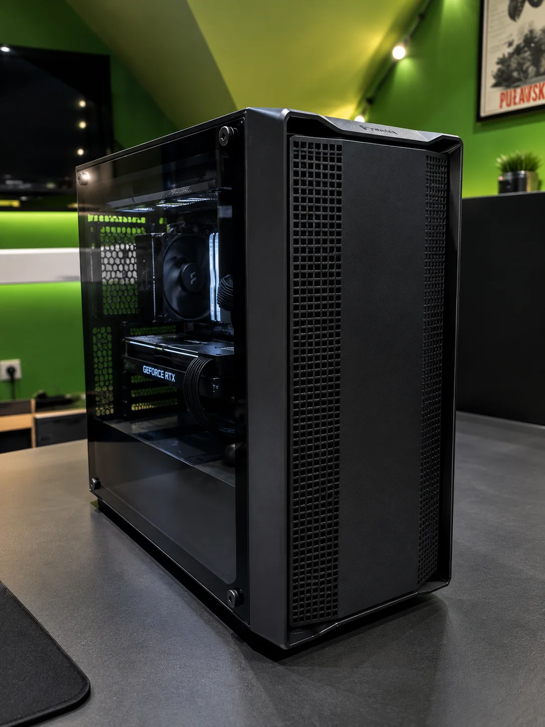 Black PC with a glass panel and a GeForce RTX graphics card on a desk in a green room