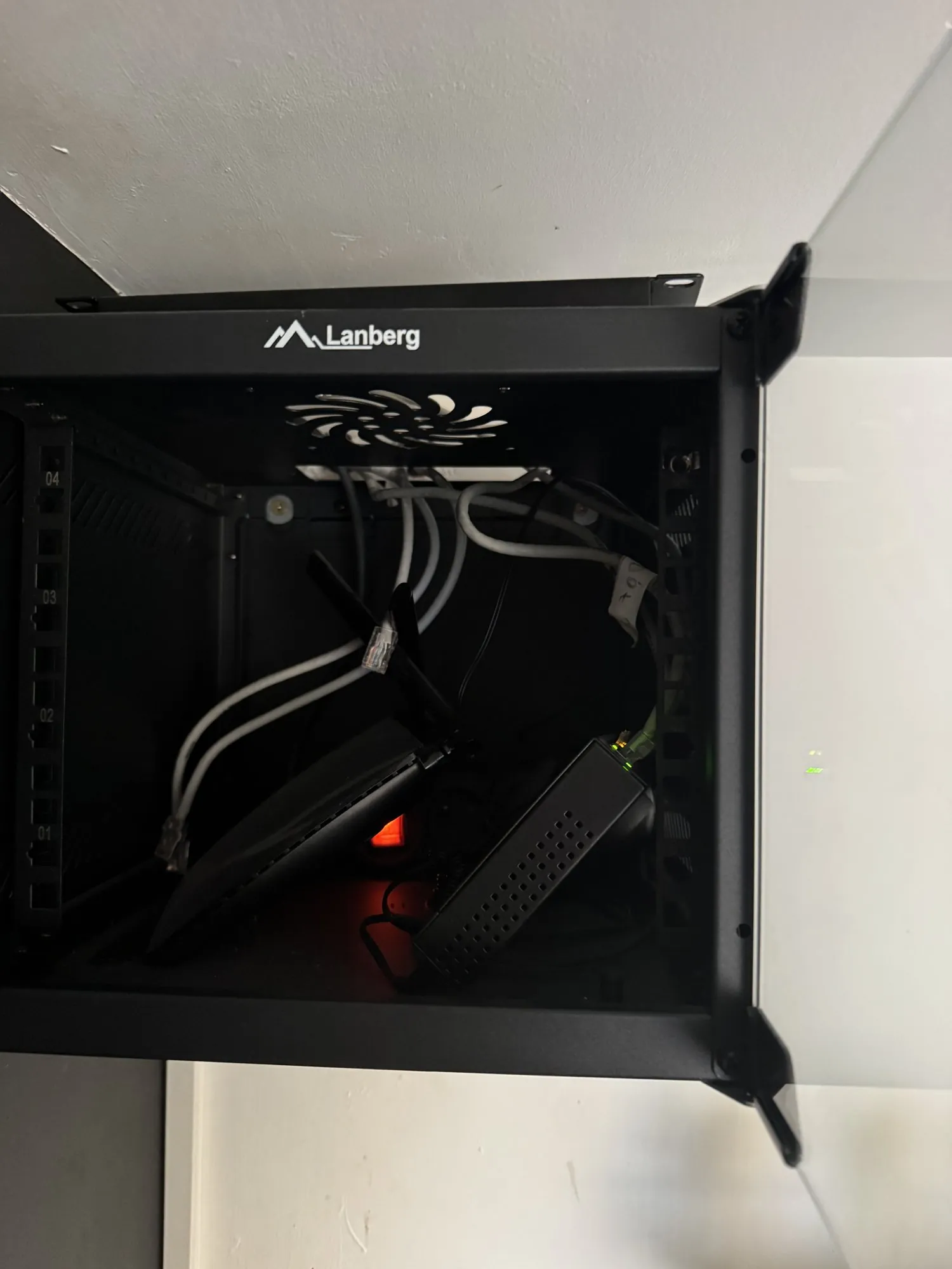 Inside a wall-mounted cabinet with no patch panel, cables placed haphazardly